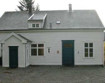 Kvitmalt trehus frå attenhundretalet med to innganger på fasaden