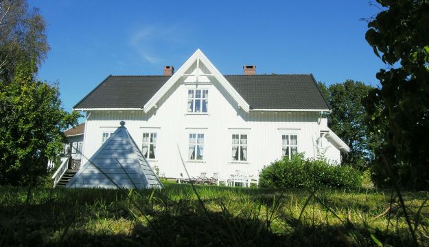 Hvitmalt hus med hage i forgrunnen