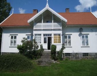 Hvitt trehus med ark over to etasjer ,sveitserstil, hage foran