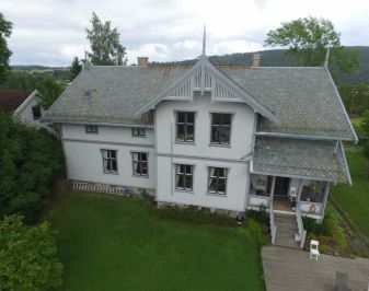 Dronebilde av Fet prestebolig. Hvit trebygning fra tidlig nittenhundretall