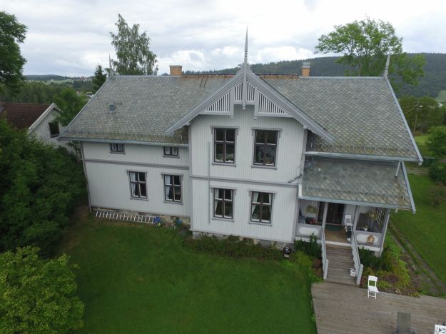 Dronebilde av Fet prestebolig. Hvit trebygning fra tidlig nittenhundretall