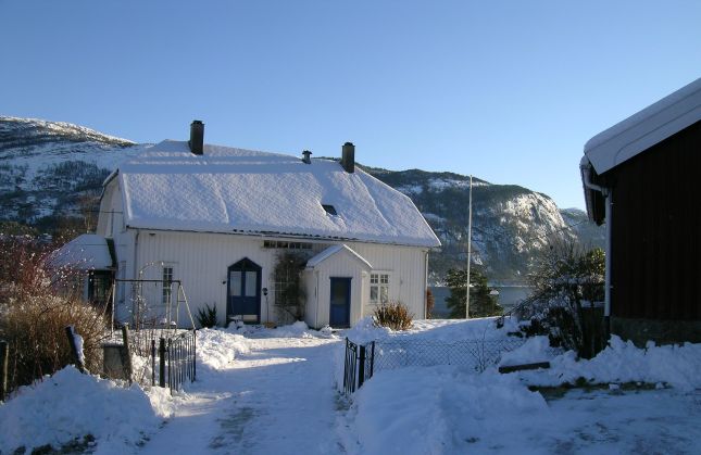 Gårdstun med hvitt våningshus. Vinterbilde