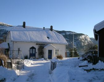 Gårdstun med hvitt våningshus. Vinterbilde