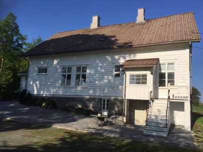 Gammelt hvitmalt trehus med kjellernedgang