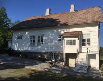 Gammelt hvitmalt trehus med kjellernedgang