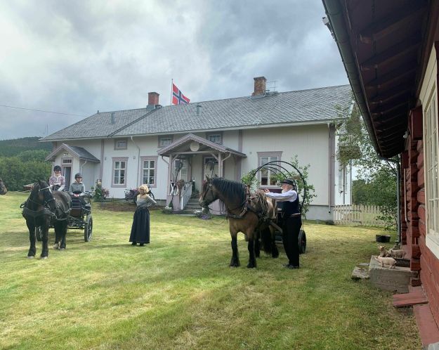 Mennesker og hest med kjerre foran prestebolig.