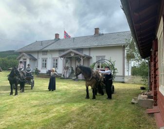 Mennesker og hest med kjerre foran prestebolig.