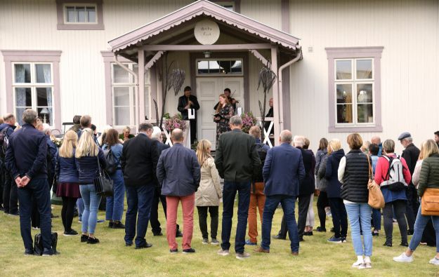 Alvdal prestegård. Forsamling av mennesker foran rosa trehus. Foto