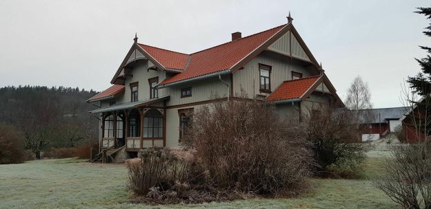 Stort grønnmalt hus med hage i forkant