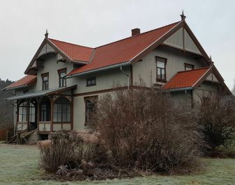 Stort grønnmalt hus med hage i forkant