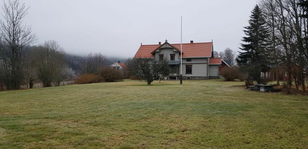 Presteboligen med hagen og flaggstang i forgrunnen