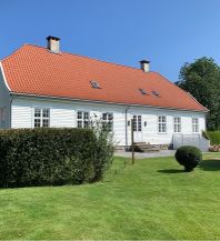 Hvitmalt hus med hage og hekk