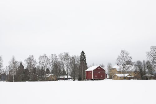 Prestegården med rødt stabbur og hovedbygningen i vinterdrakt