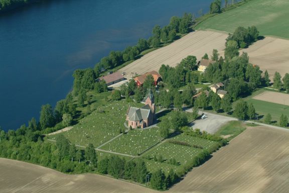 dronebilde om sommeren av kirke og gårdsbruk ved elv, Glomma