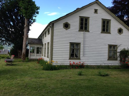 Kvitmalt hus med grønne hjørnekasser og vinduer