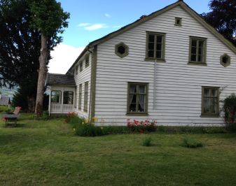 Kvitmalt hus med grønne hjørnekasser og vinduer