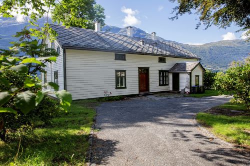 Ullensvang prestegard ligger i Lofthus i Hardanger. Hvitt trehus på sommerstid. Foto