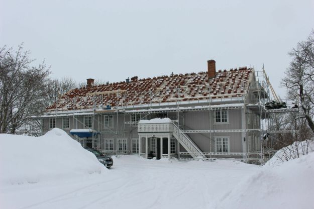 Østre Toten prestegård. Hvitt trehus under oppussing i snødekket landskap. Foto