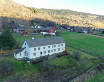 Øyer prestegård en to etasjes meget lang trebygning i en helling i landskapet